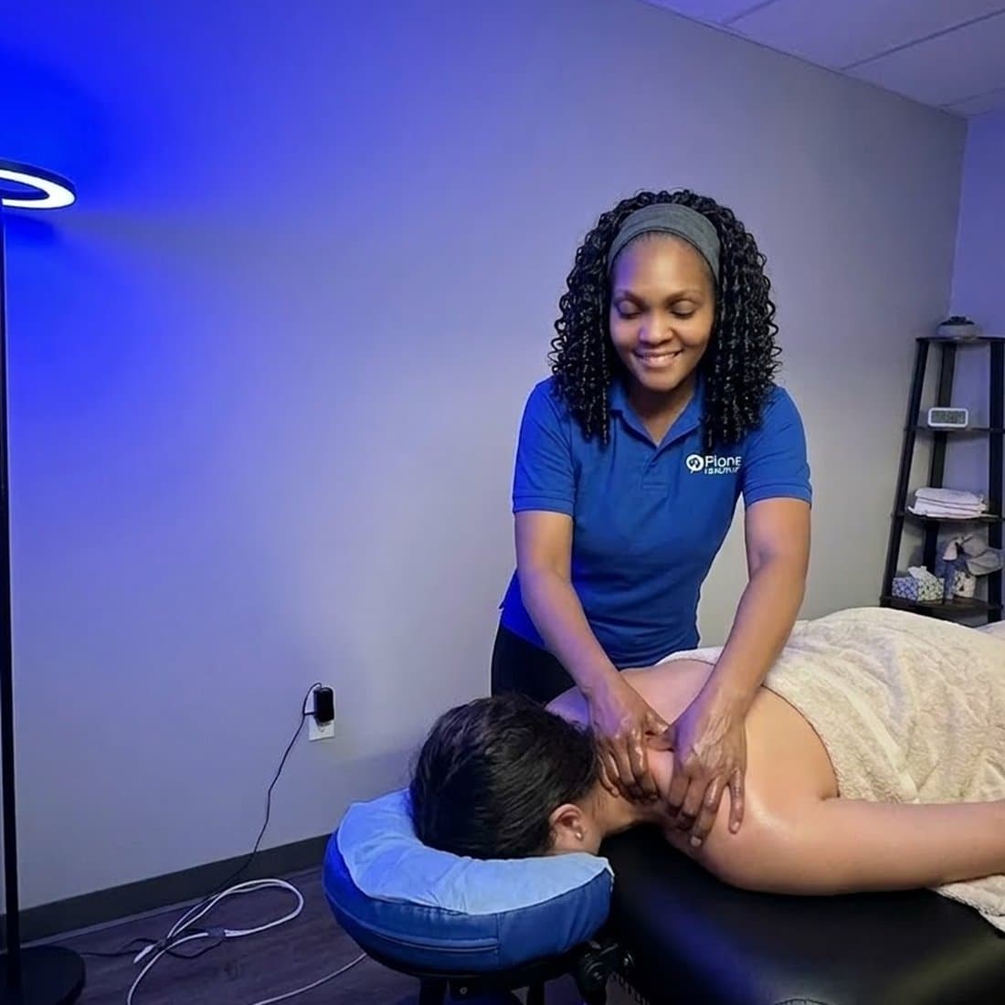 Registered massage therapist treating a patient’s shoulders in a softly lit treatment room at Planet Health Care