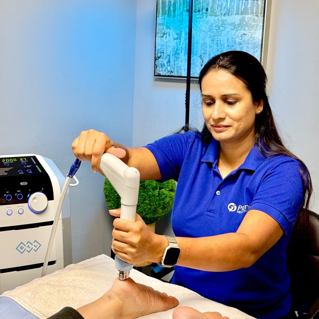 Hiral Desai applying radial shockwave therapy to a patient foot at Planet Health Care